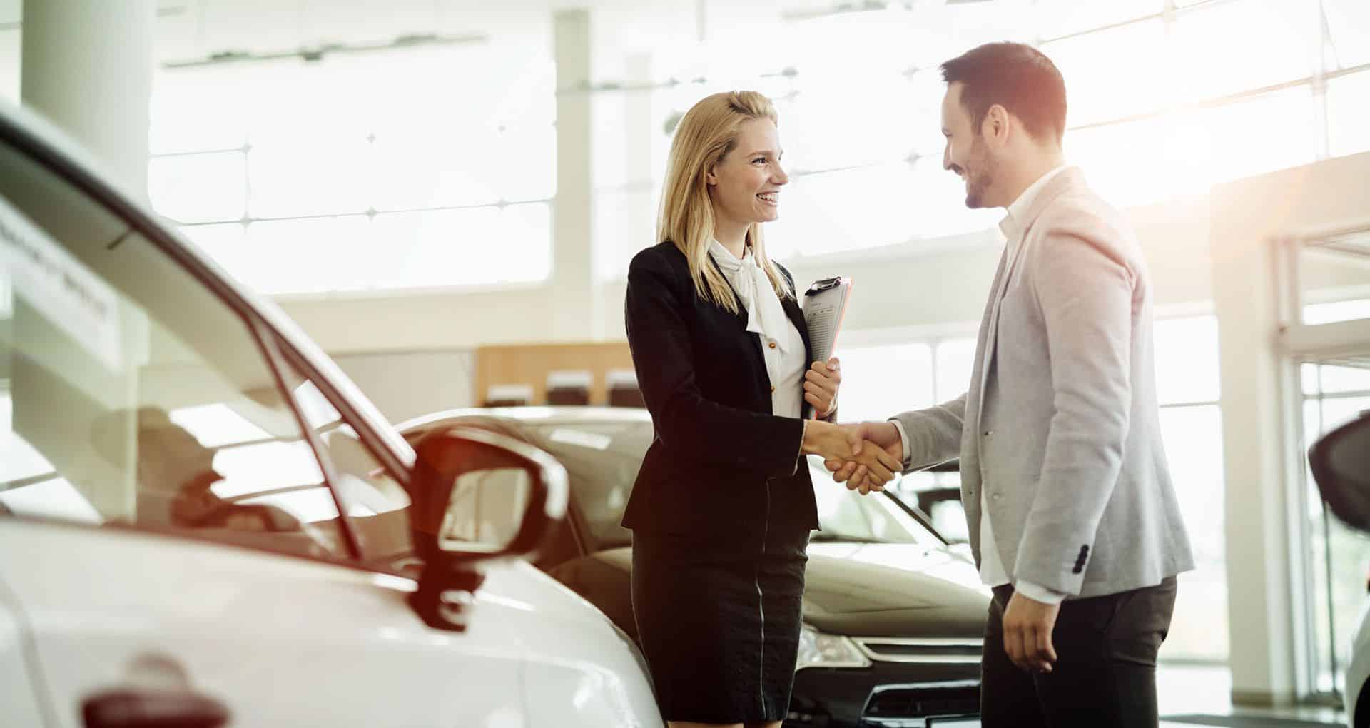 A man shaking hands with a sales rep at a car dealership